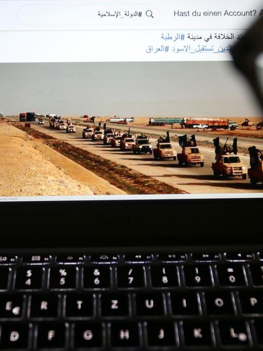 Eine junge Frau schaut in Köln auf einen Computermonitor, auf dem einer Website mit Propaganda des IS zu sehen ist.