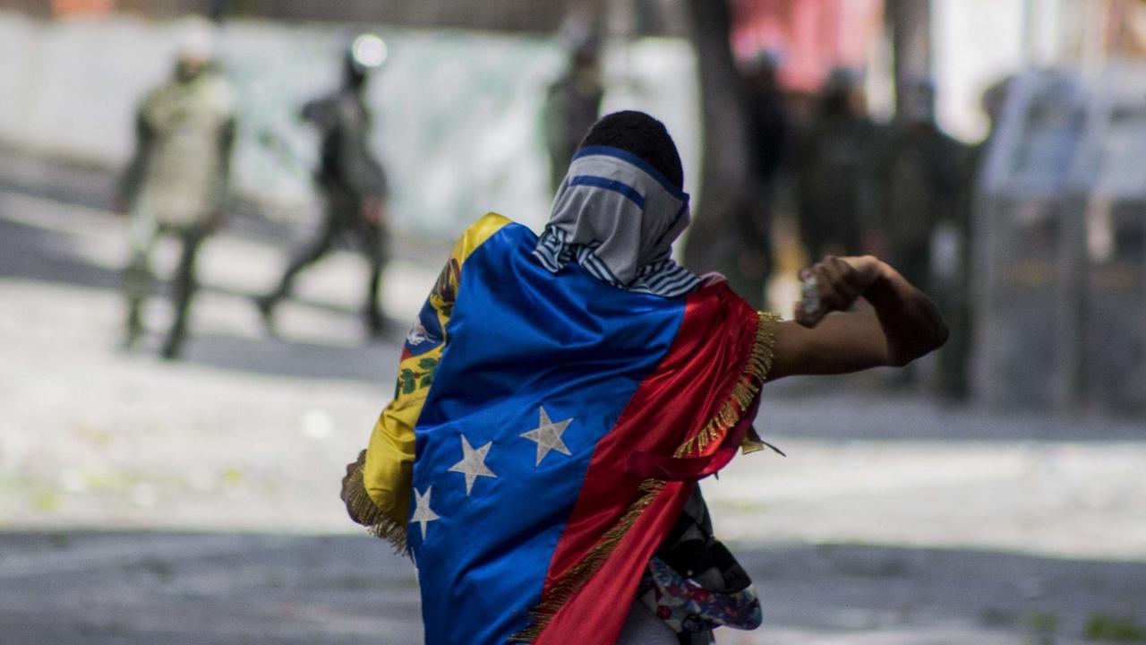 Ein Demonstrant wirft am 26.7.2017 in Venezuelas Hauptstadt Caracas Steine gegen die Nationalgarde.