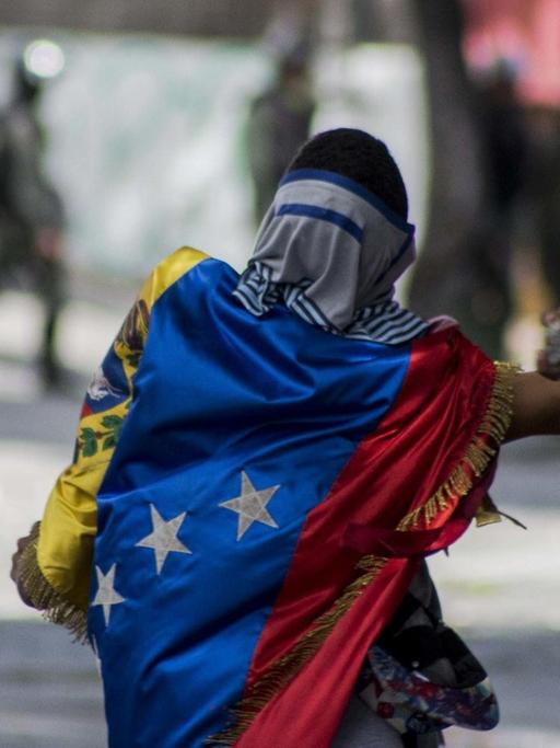 Ein Demonstrant wirft am 26.7.2017 in Venezuelas Hauptstadt Caracas Steine gegen die Nationalgarde.