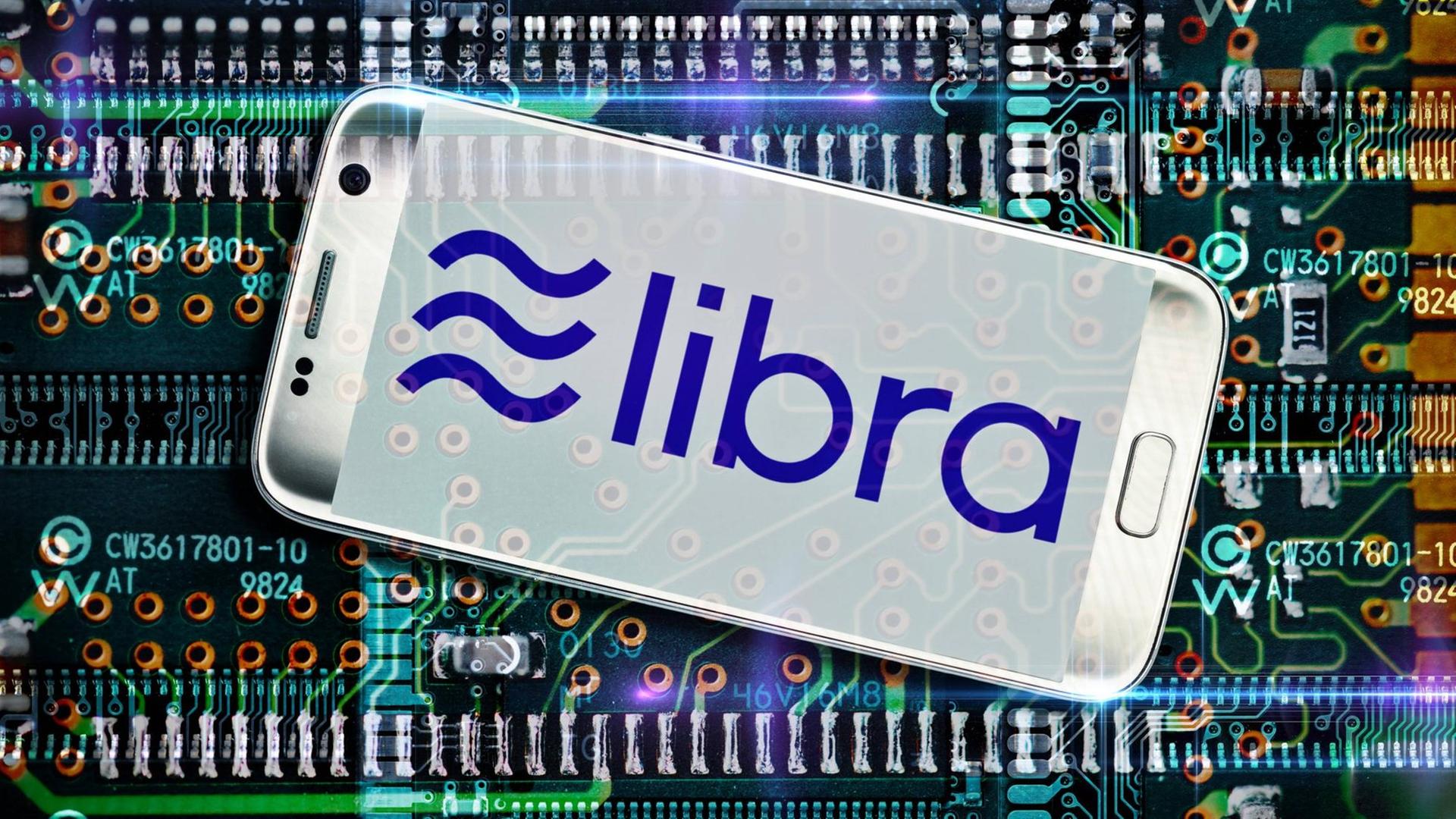 Schriftzug der Facebook-Kryptowährung Libra auf einem Smartphone-Display, im Hintergrund ist eine Platine zu sehen (Fotomontage)