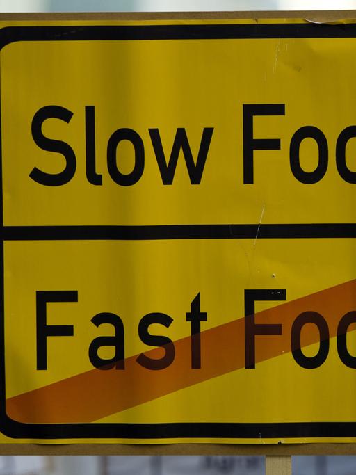 Ein Schild mit der Aufschrift "Slow Food - Fast Food" ist in Berlin auf einer Demonstration zu sehen.