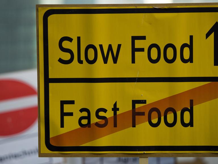 Ein Schild mit der Aufschrift "Slow Food - Fast Food" ist in Berlin auf einer Demonstration zu sehen.