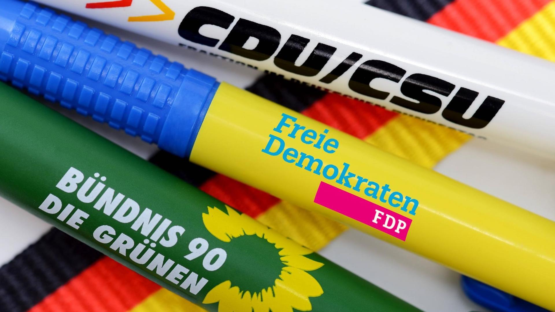 Kugelschreiber der Parteien CDU/CSU, FDP und Bündnis 90 die Grünen liegen auf einer Deutschlandfahne
