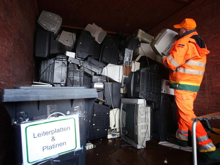 Ein Mitarbeiter der Hamburger Stadtreinigung stapelt am 04.02.2013 ausrangierte Fernseher und Monitore in einem Sammelcontainer für Elektroschrott auf dem Recyclinghof Bahrenfeld in Hamburg.