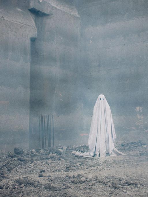 Figur mit Bettlaken und Schlitzen für die Augen als Gespenst. Der Schauspieler Casey Affleck in dem US-amerikanischen Spielfilm "A Ghost Story" aus dem Jahr 2017