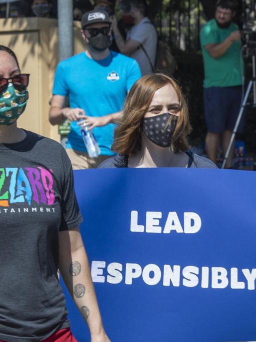 Zwei Frauen protestieren mit Plakat für mehr Verantwortung bei dem Videospielunternehmen Activision Blizzard.
