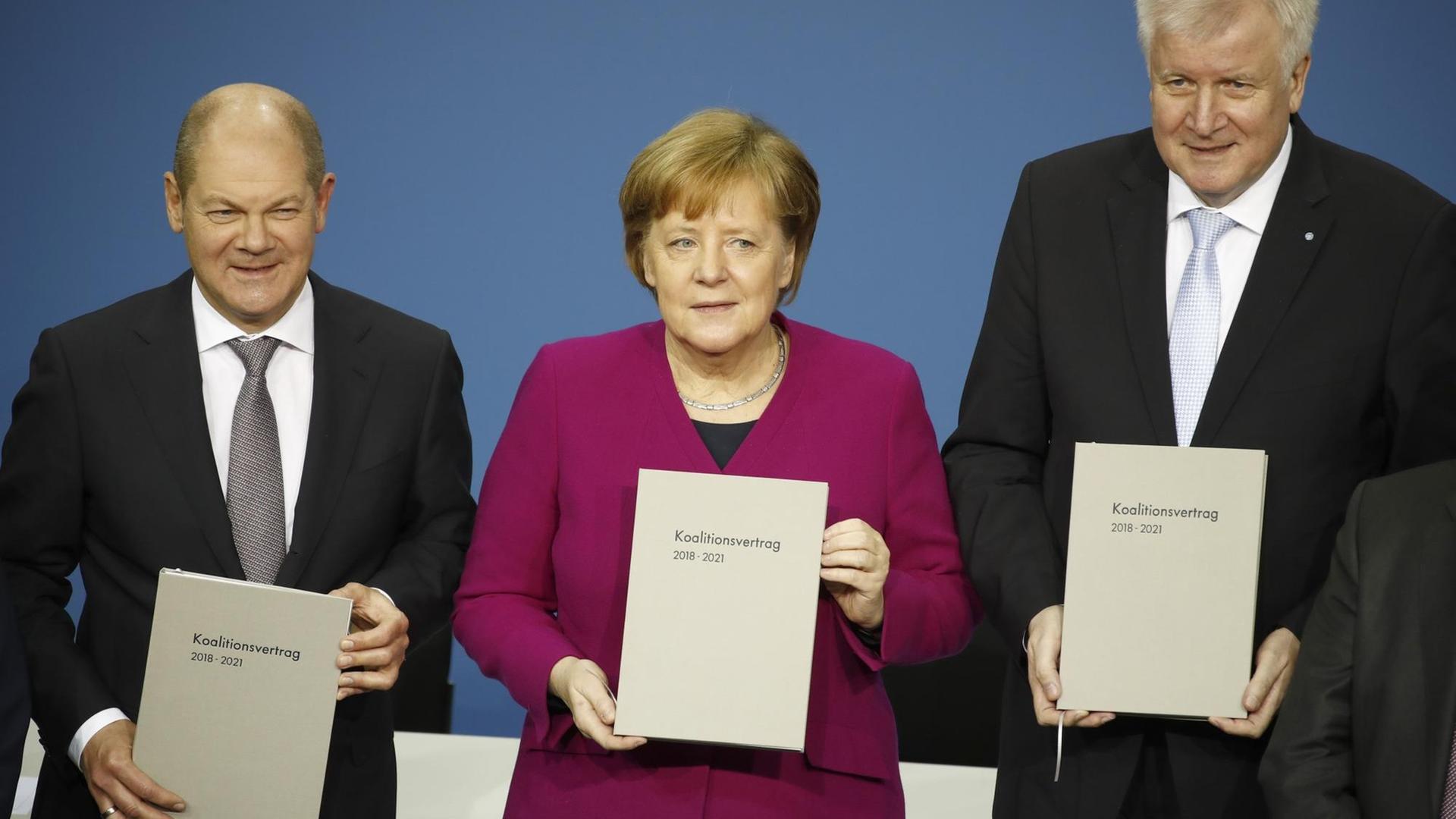 Bundeskanzlerin Angela Merkel (CDU), der CSU-Vorsitzende Horst Seehofer (r) und der kommissarische SPD-Vorsitzende Olaf Scholz unterzeichnen im Paul-Löbe-Haus den Koalitionsvertrag.