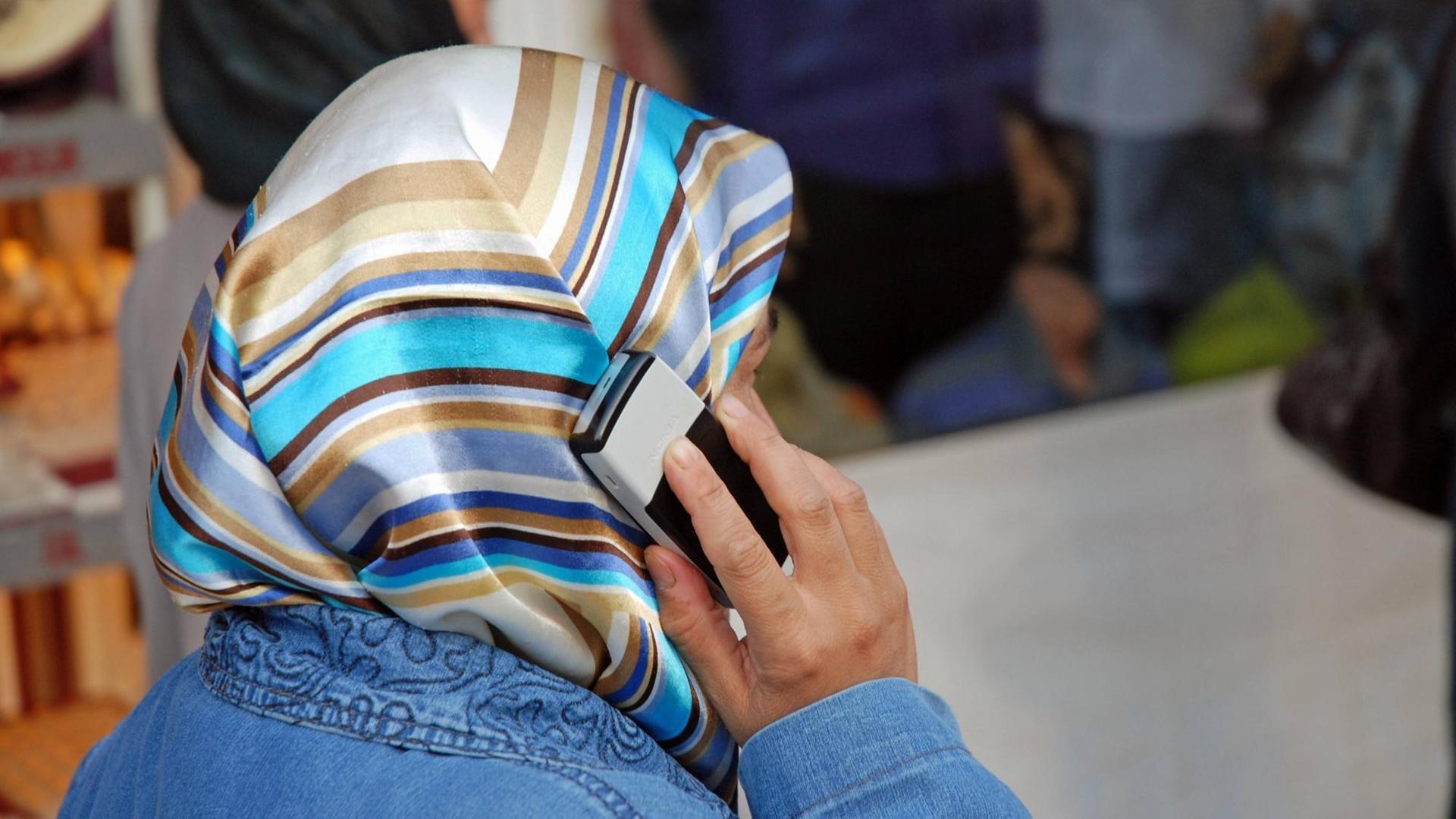 Eine muslimische Frau mit Kopftuch beim Telefonieren