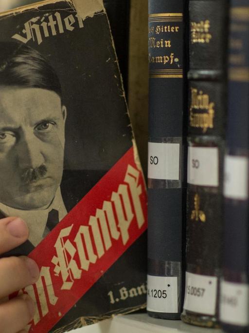 Man sieht, wie jemand eine Ausgabe von Hitlers "Mein Kampf" aus dem Jahr 1933 aus dem Regal zieht.
