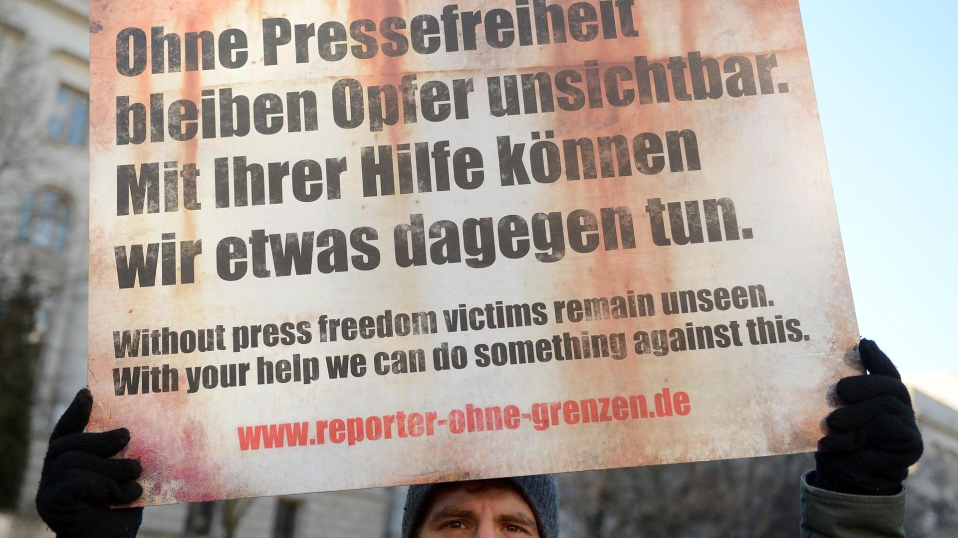 Mann hält Protestschild für die Pressefreiheit in die Luft