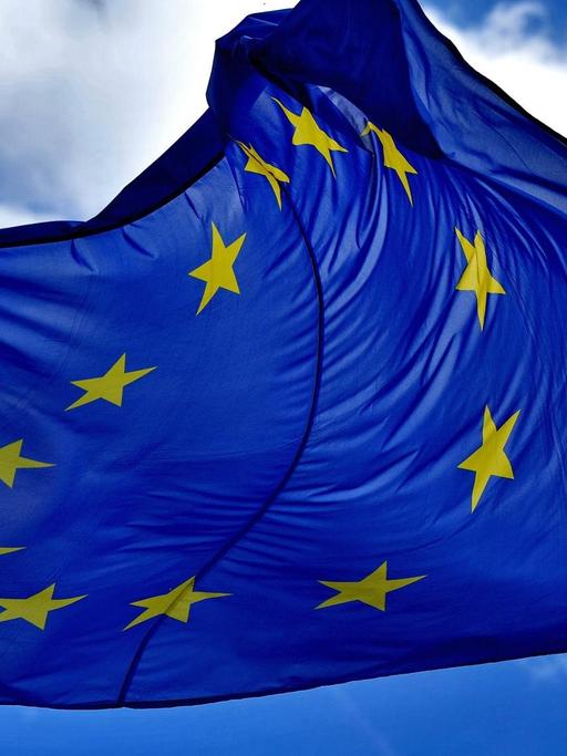 Eine EU-Fahne flattert vor fast wolkenlosem Himmel im Wind.