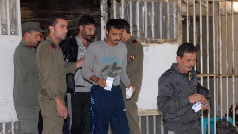 Am 11. Juni 2014 werden diese Häftlinge aus einem Gefängnis in Damasakus entlassen. Das Bild zeigt Menschen, die mit Papieren in der Hand einen vergitterten Bereich verlassen dürfen, Wärter sehen zu.
