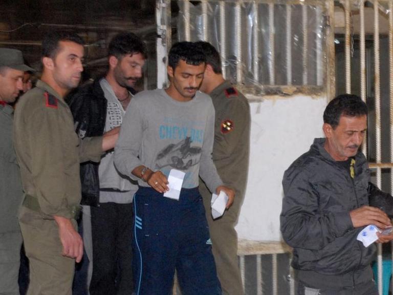 Am 11. Juni 2014 werden diese Häftlinge aus einem Gefängnis in Damasakus entlassen. Das Bild zeigt Menschen, die mit Papieren in der Hand einen vergitterten Bereich verlassen dürfen, Wärter sehen zu.