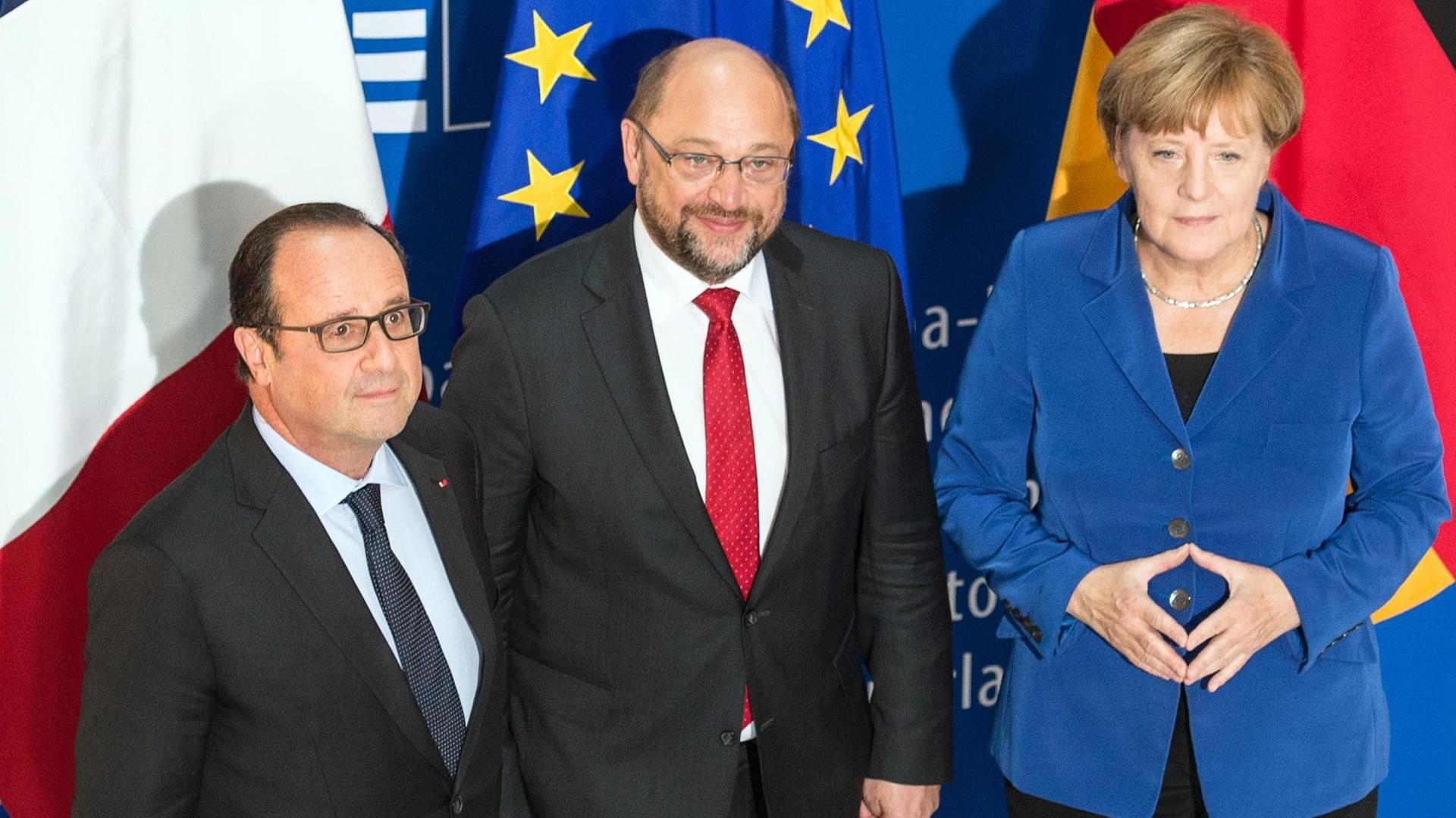 François Hollande, Martin Schulz und Angela Merkel vor den Flaggen Frankreichs, der EU und Deutschlands.