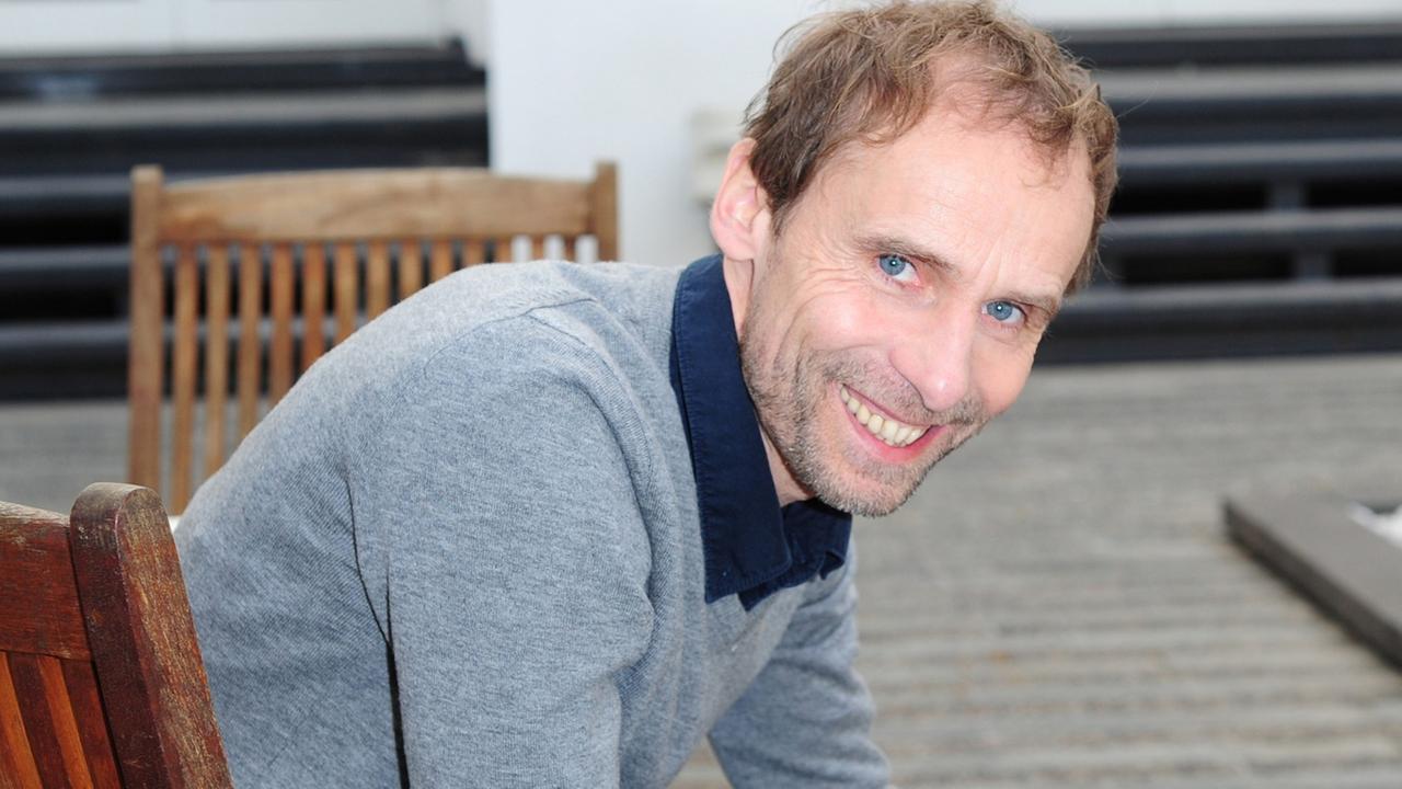 Der Dokumentarfilmer und Regisseur Jörg Schütte sitzt in einem braunen Holzstuhl auf einer Terrasse des Hamburger Hotels Kempinski.