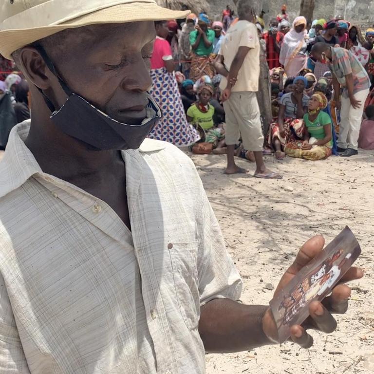 Ein Mann in einem Flüchtlingscamp auf der mosambikanischen Insel Quirimba zeigt ein Foto seiner Familie.