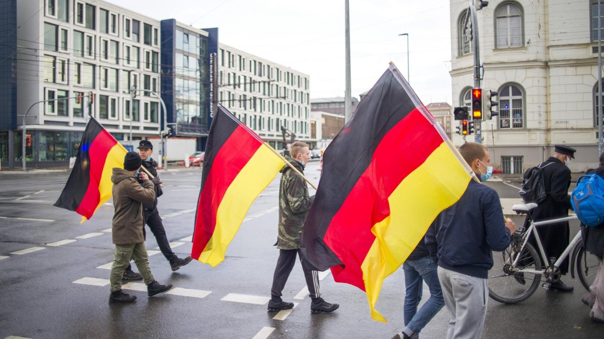Deutschlandfahnen tragen Teilnehmer einer Demonstration am Abend in der City von Rostock. Jeden Montag kommt es in mehreren Städten von Mecklenburg-Vorpommern zu Demonstrationen gegen die Maßnahmen zur Eindämmung der Corona-Pandemie.