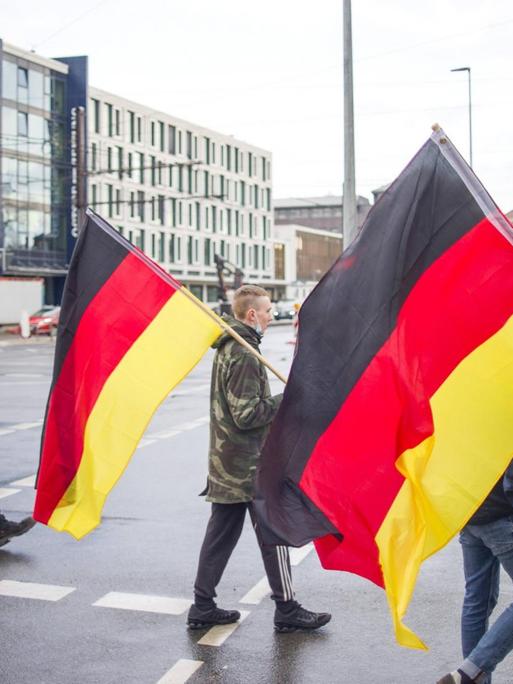 Deutschlandfahnen tragen Teilnehmer einer Demonstration am Abend in der City von Rostock. Jeden Montag kommt es in mehreren Städten von Mecklenburg-Vorpommern zu Demonstrationen gegen die Maßnahmen zur Eindämmung der Corona-Pandemie.