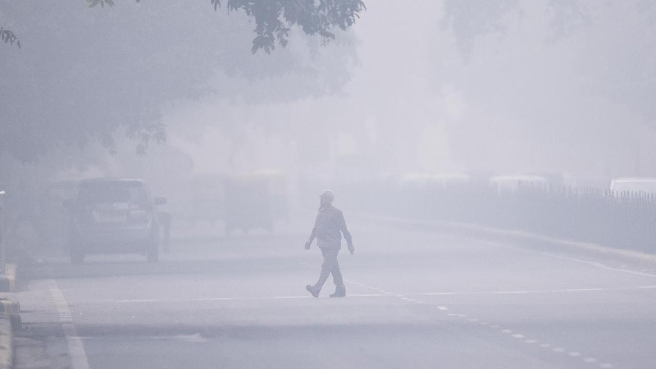 Das Foto zeigt einen Mann auf einer Straße in Neu-Delhi in Indien. Es herrscht Smog, die Sicht ist schlecht.