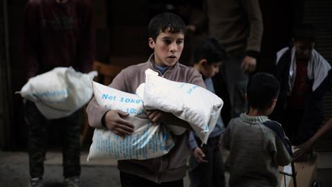 Ein syrischer Junge in Kafr Batna mit Hilfsgütern des World Food Programme