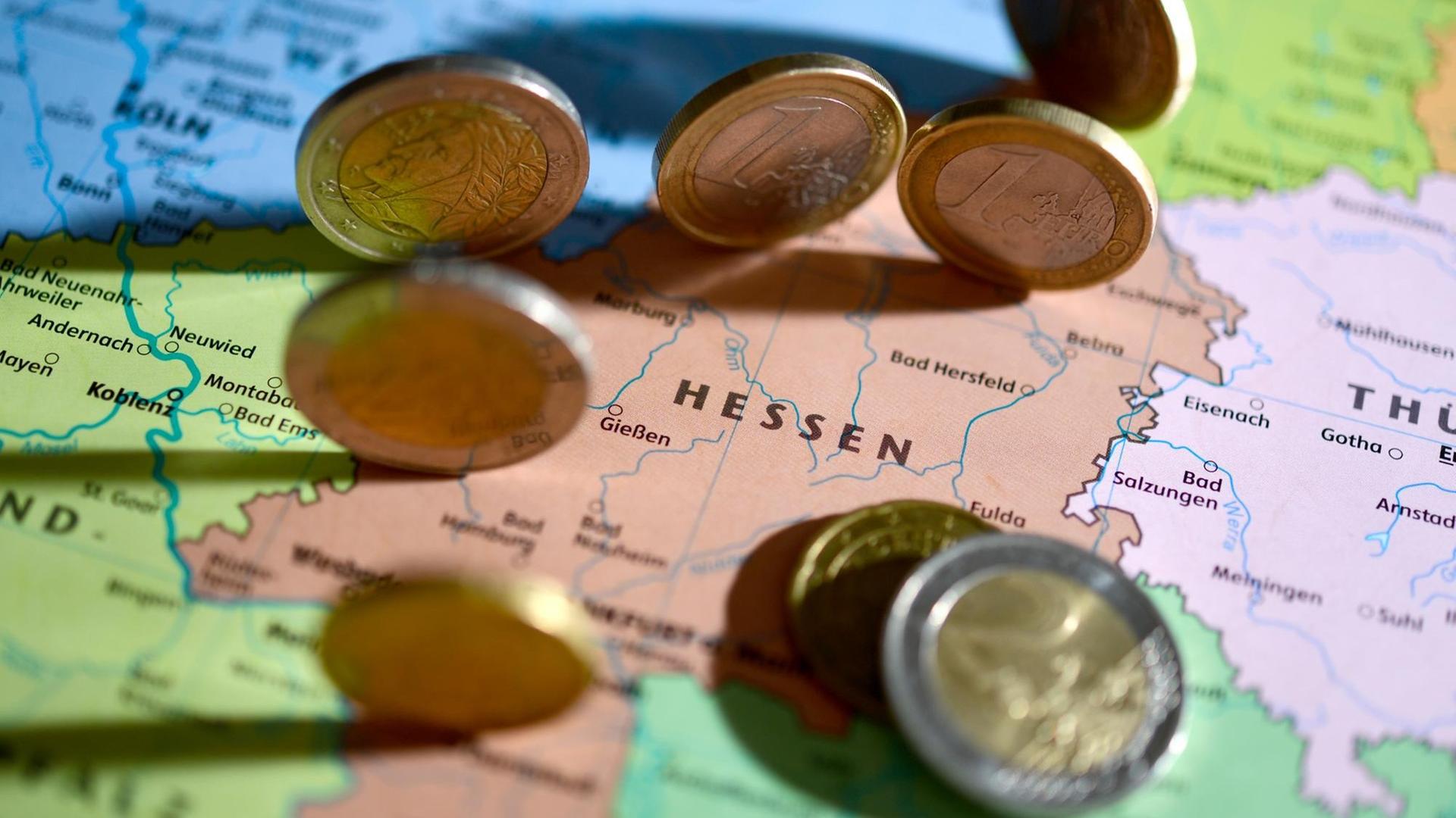 Euro-Münzen liegen auf einer Landkarte, zu sehen sind das Bundesland Hessen und die benachbarten Bundesländer.