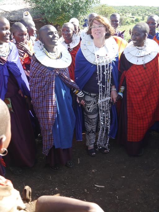 Die Autorin Bettina Brand (Mitte) steht in Tansania zwischen Einheimischen Frauen.