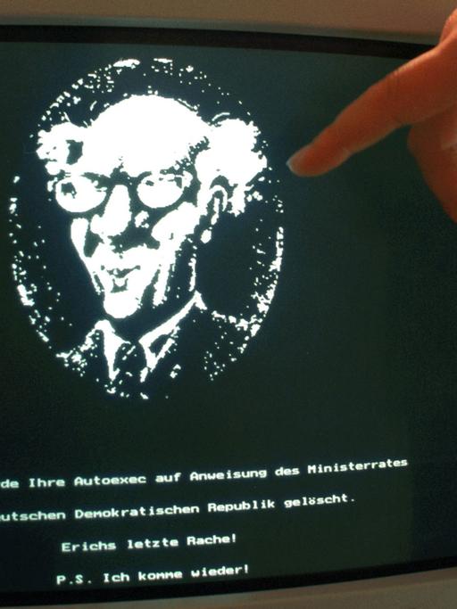 Ein schwarzer Computerbildschirm, auf dem in Weiß das Porträt Erich Honeckers zu sehen ist, darunter die Aufschrift: "Hiermit wurde Ihre Autoexec auf Anweisung des Ministerrates der Deutschen Demokratischen Republik gelöscht. Erichs letzte rache! P.S. Ich komme wieder!".
