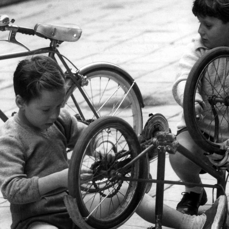 Zwei Kinder in Venedig brauchen nicht bei jeder Kleinigkeit in ein Fachgeschäft zu gehen. Sie reparieren kleinere Macken an ihren Drahteseln einfach selbst. Aufnahme vom 27.09.1960