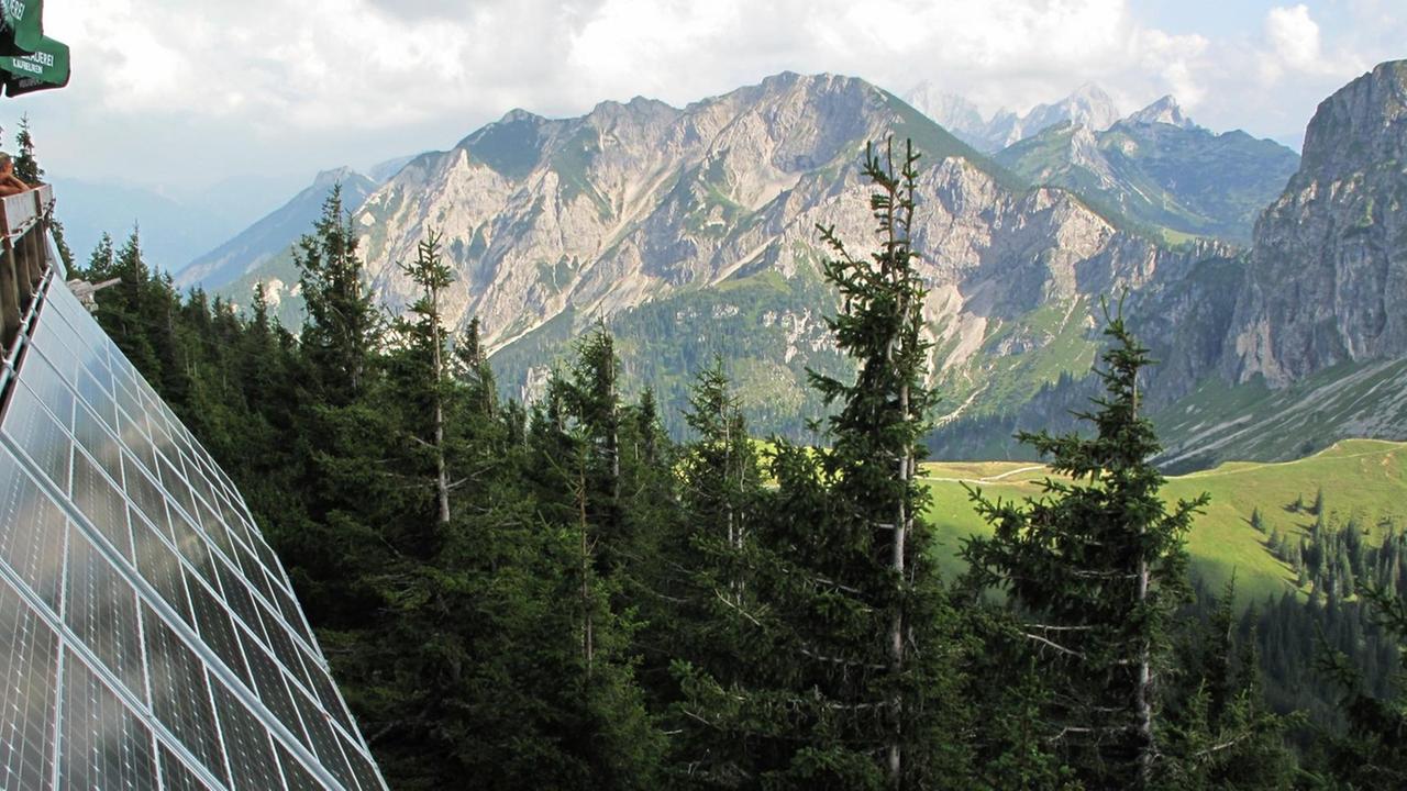 Blick von einer Alpenhütte mit modernen Solarzellen auf die Berge Breitenberg und Aggenstein.