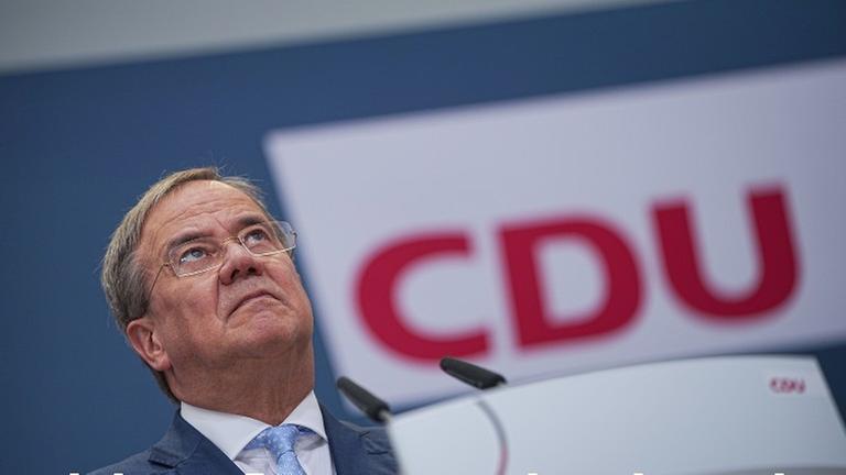 Armin Laschet schaut sorgenvoll vor einem Logo der CDU. 