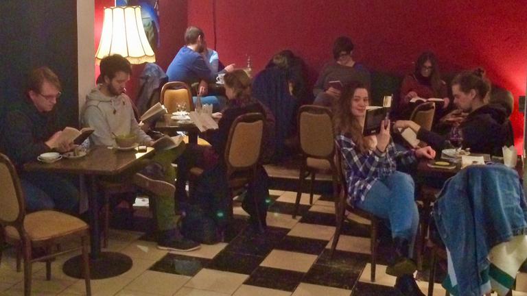Silent-reading-party im Kieler Café Godot: Junge Menschen sitzen im Dämmerlicht und lesen.
