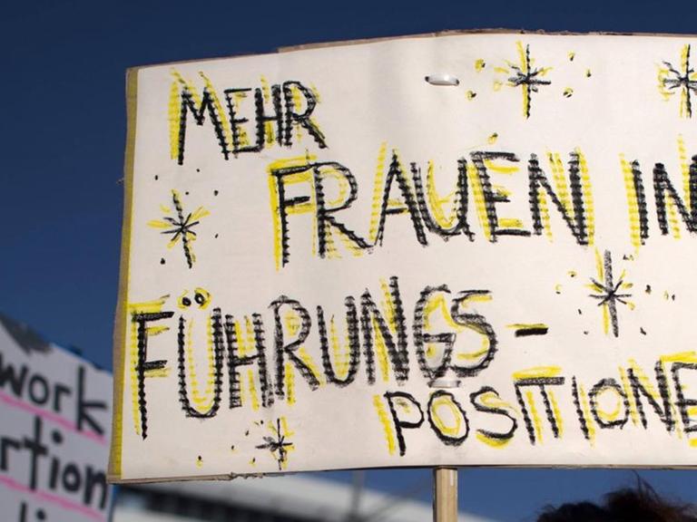 Eine Demonstrantin hält ein Schild mit der Aufschrift "Mehr Frauen in Führungspositionen" bei einer Kundgebung in Berlin.