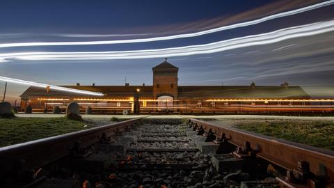 Lichter von vorbeifahrenden Autos sind vor dem Eingangsportal des ehemaligen Konzentrationslagers Auschwitz-Birkenau zu sehen.
