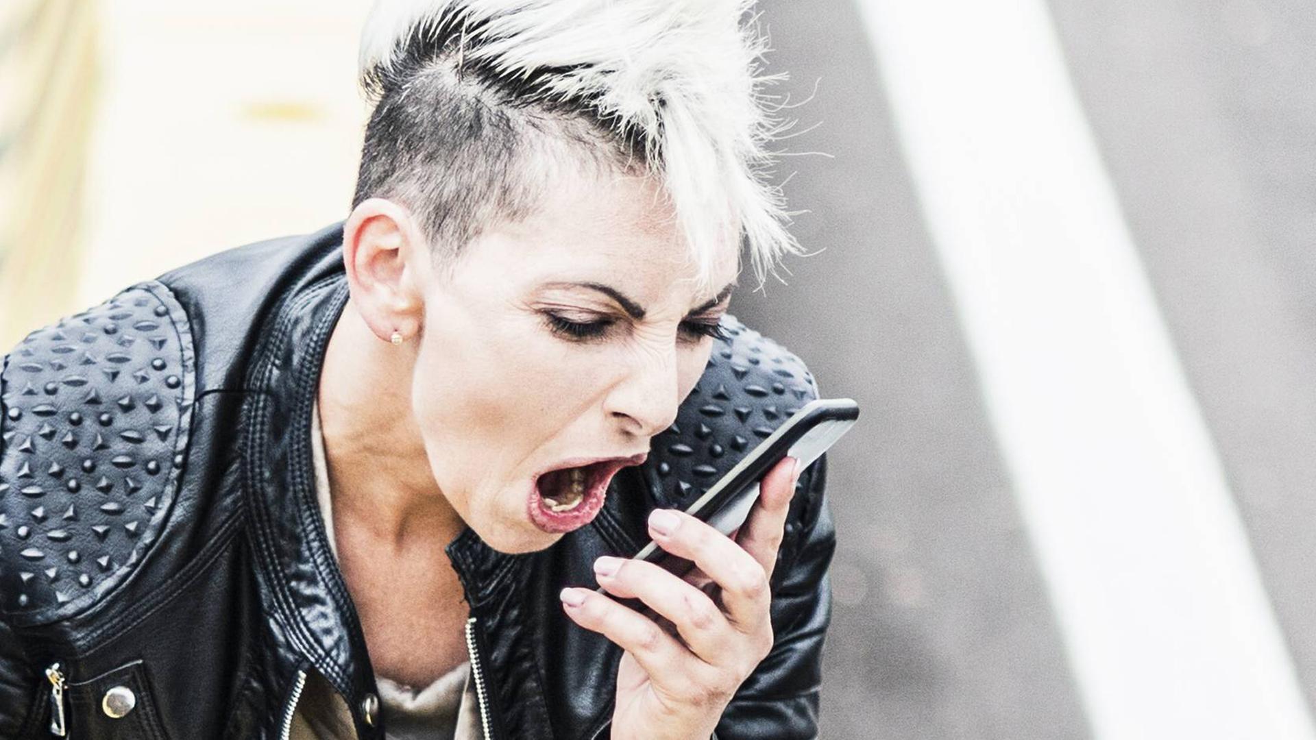 Aggressive punk woman sitting at the roadside screaming into cell phone model released Symbolfoto PUBLICATIONxINxGERxSUIxAUTxHUNxONLY GIOF04436