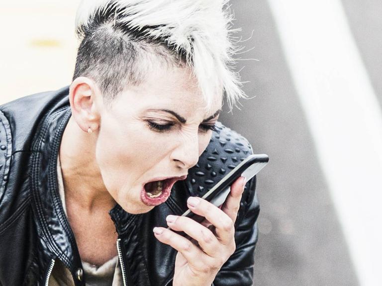 Aggressive punk woman sitting at the roadside screaming into cell phone model released Symbolfoto PUBLICATIONxINxGERxSUIxAUTxHUNxONLY GIOF04436
