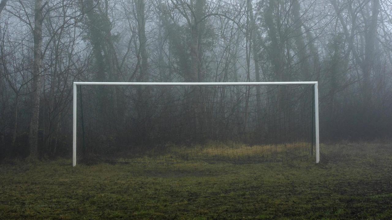 Ein Fußballtor steht im Nebel.