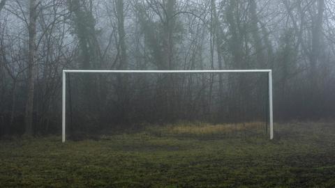 Ein Fußballtor steht im Nebel.