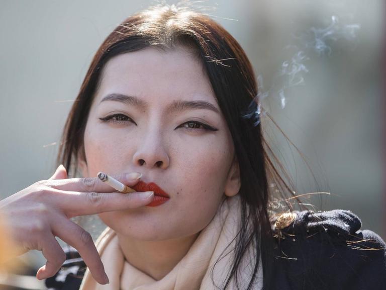 Das Bild zeigt eine rauchende Frau in Peking.