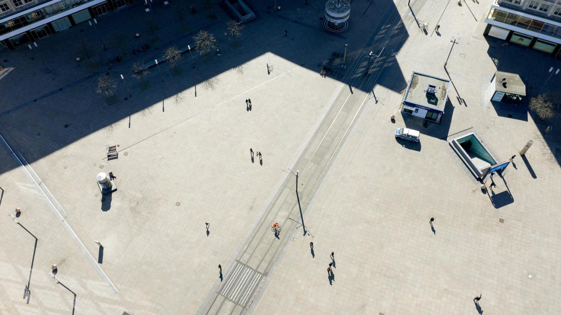 Vogelperspektive auf den Alexanderplatz, auf dem mit großem Abstand einige Menschen laufen.