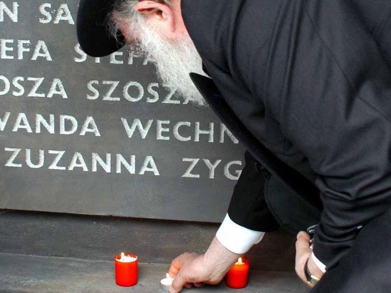 Ein Mann stellt am 3.6.2004 bei Einweihung der Gedenkstätte für die Holocaust-Opfer des ehemaligen deutschen Vernichtungslagers im ostpolnischen Belzec an einer Gedenktafel eine Kerze auf.