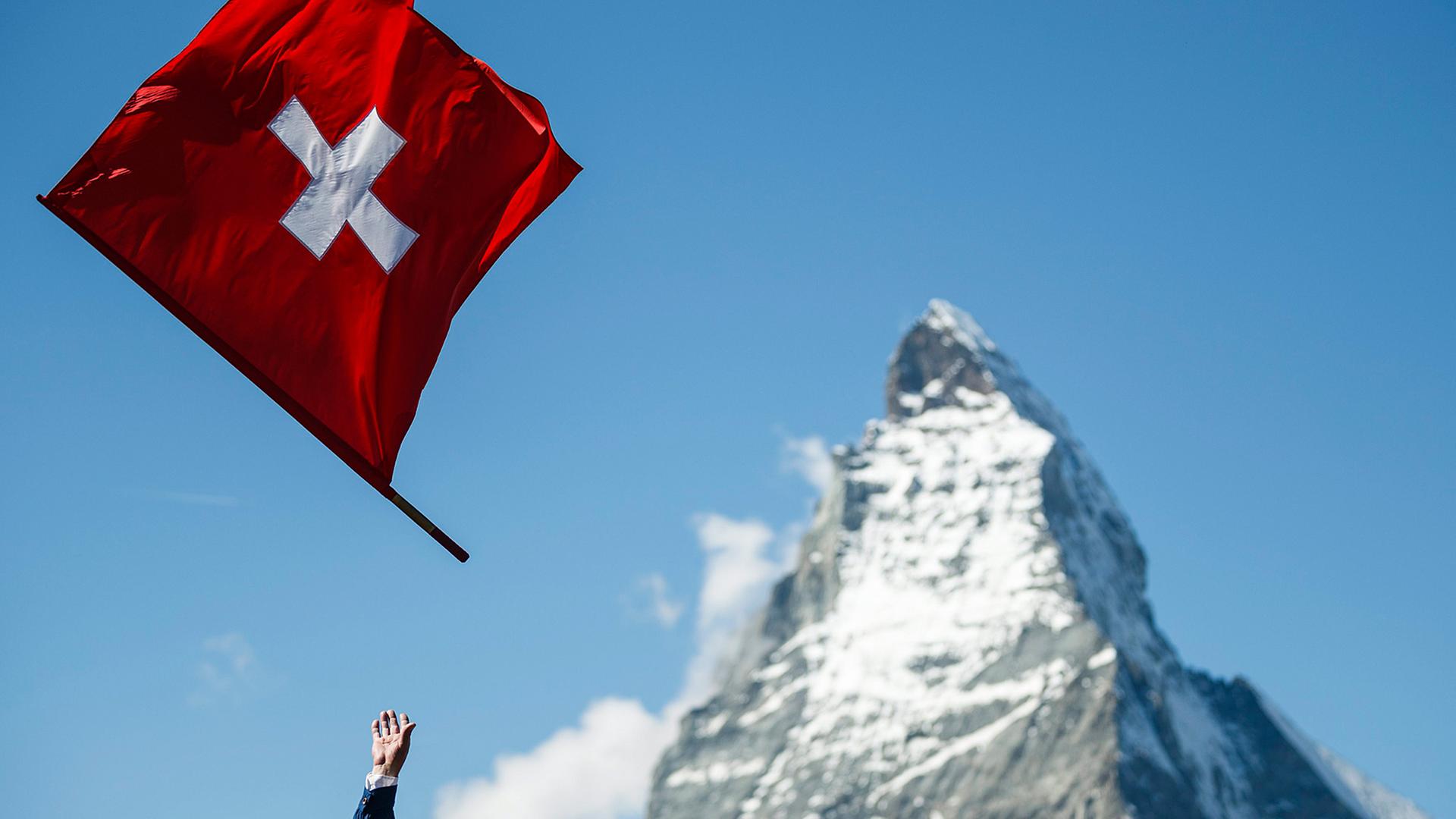 Eine hochgeworfene Schweizer Flagge vor der Spitze des Matterhorns