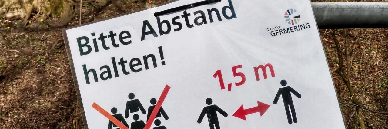 Auf einem an einem Laternenpfahl angebrachten Zettel steht: "Bitte Abstand halten". DIe Deutschen sind angewiesen in der Öffentlichkeit einen Mindestabstand von 1,5 Metern zueinander zu halten.