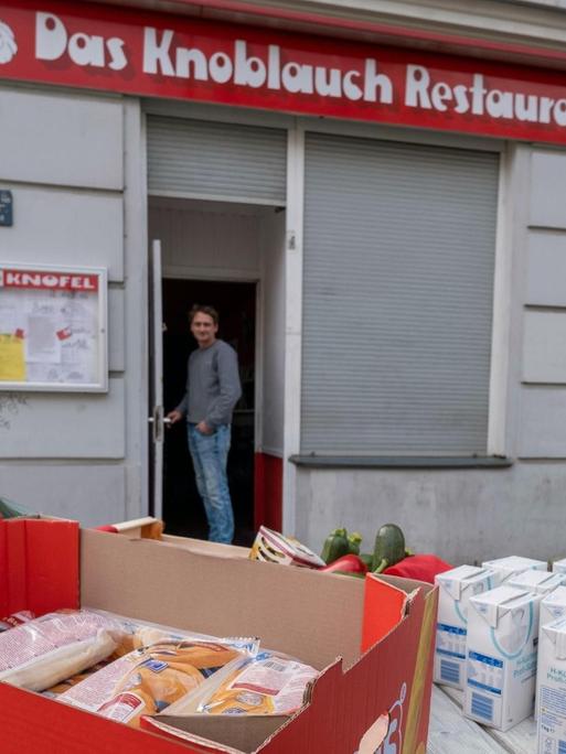 Der Besitzer des Restaurants Knofel in der Wichertstraße in Berlin-Prenzlauer Berg verschenkt wegen der Schließung seine verderblichen Lebensmittel vor seinem Geschäft.