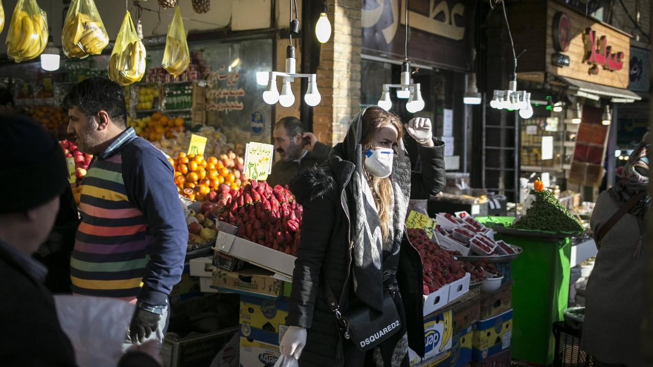 Eine Frau mit Schutzmaske steht auf einem Markt in Teheran.