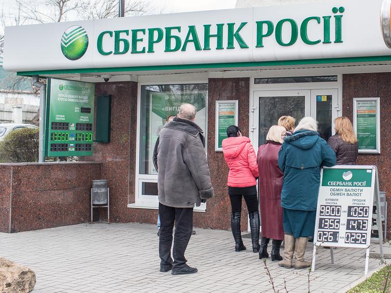 Menschen stehen am 18.03.2014 in Simferopol (Ukraine) vor einer Filiale der russischen Bank Sberbank in einer Schlange um Geld abzuheben.