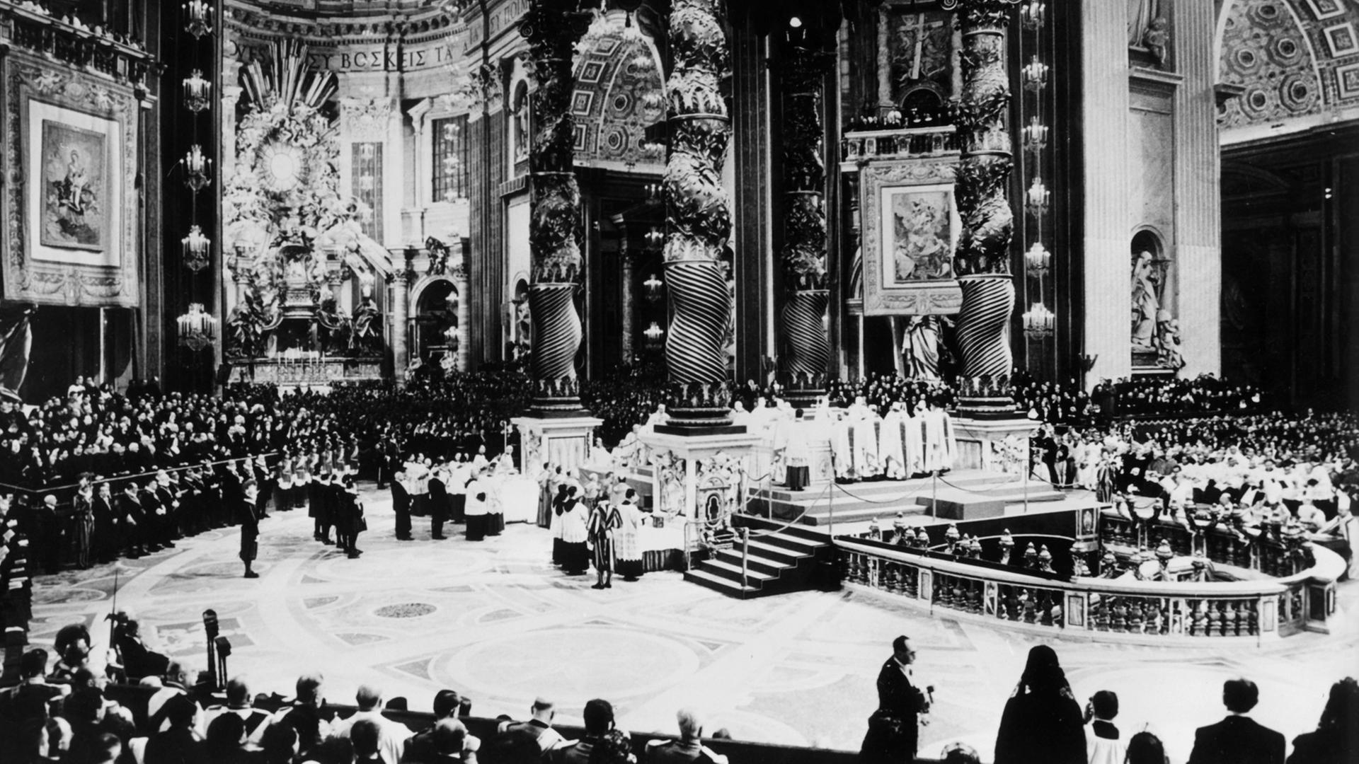 Bischöfe und Theologen sind im Inneren des Petersdoms anlässlich des Zweiten Vatikanischen Konzils versammelt. Es handelt sich um eine Aufnahme aus dem Jahr 1962.
