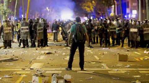 Bei Demonstartionen der Katalonischen Seperatisten am 15. Oktober 2019 in Barcelona steht ein Mann einer Reihe schwer ausgerüsteter Polizisten gegenüber, der Boden ist übersät mit Müll.