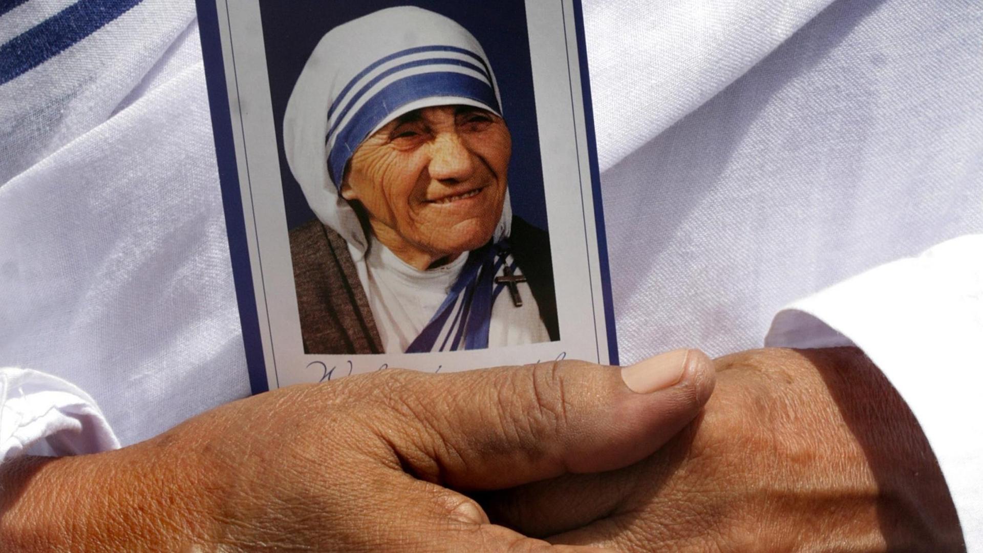 Eine Nonne hält ein Bild von Mutter Teresa in den Händen. Eine Nonne hält ein Bild von Mutter Teresa in den Händen.