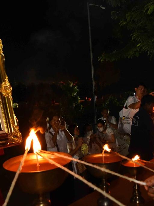 Ein buddhistischer Mönch entzündet eine Kerze in Gedenken an den verstorbenen König Bhumibol