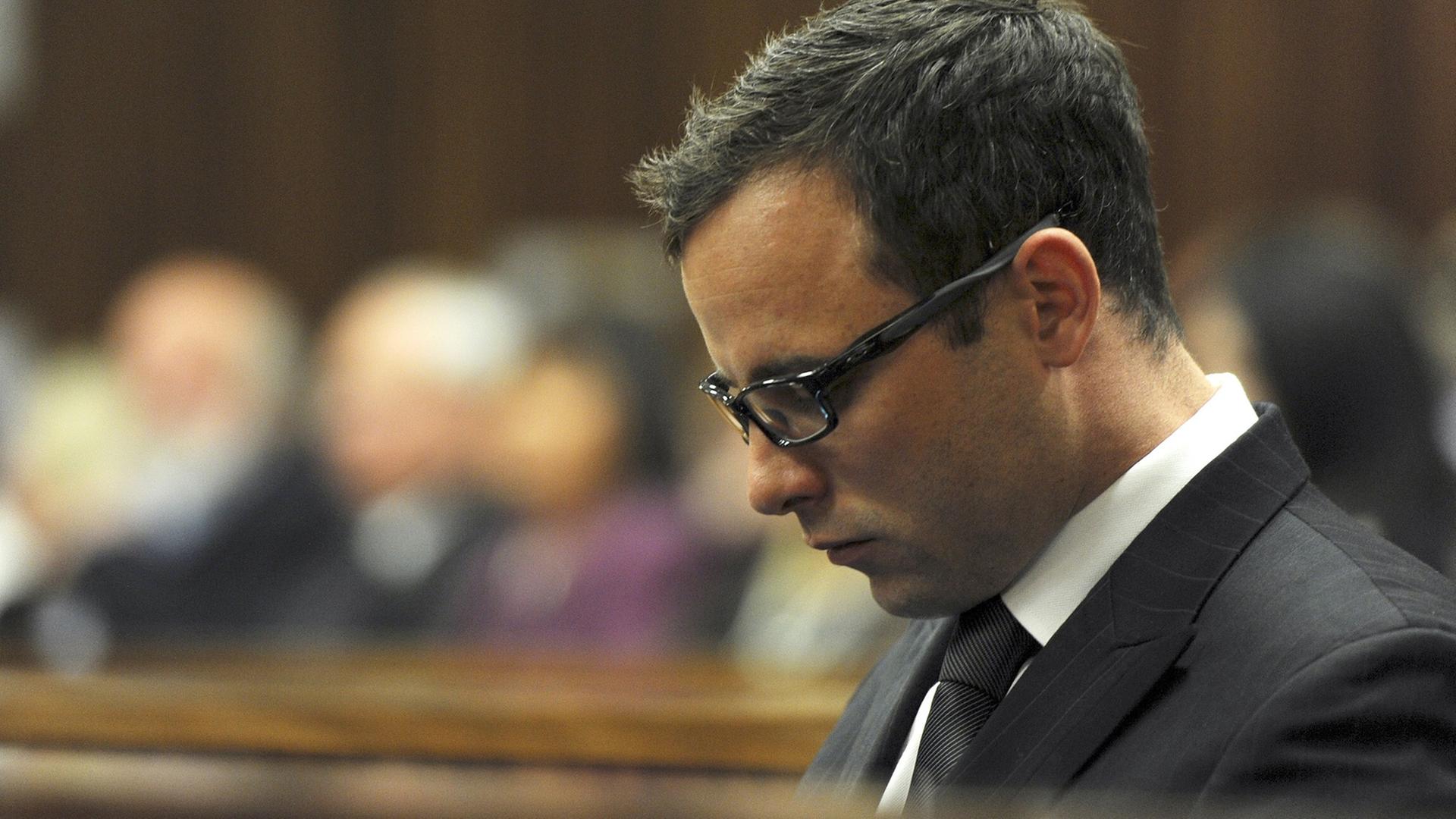 Pistorius mit gesenktem Kopf und Brille. Im Hintergrund unscharf Zuschauer im Gericht.